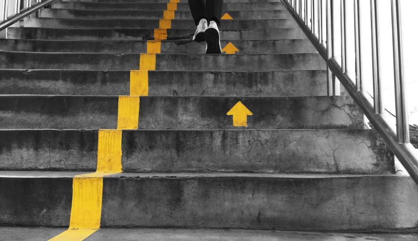 A person walking up stairs with a yellow line in the middle